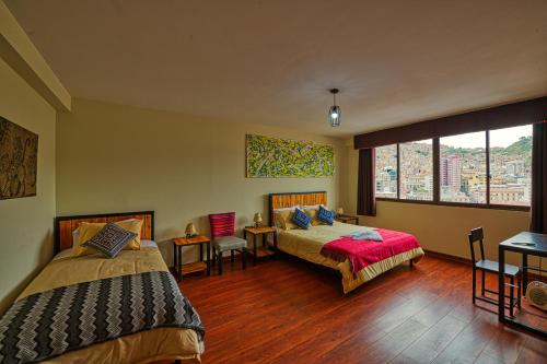 a bedroom with two beds and a large window at ISKAY BOUTIQUE HOSTEL in La Paz