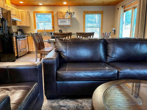 a living room with a leather couch and a kitchen at Cascade Mountain Chalet in Wilmington