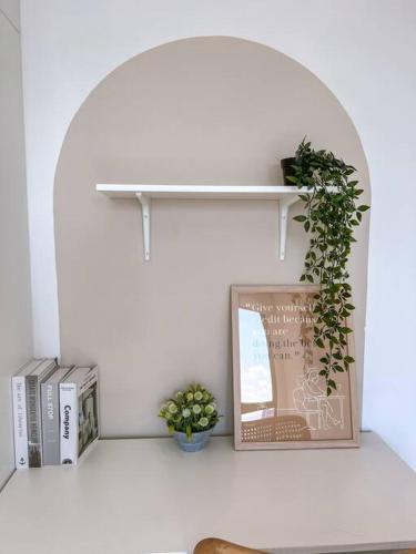 a shelf with a picture and some books and a plant at Kenwingston Skyloft Apartment Doorsteps to BRT Subang USJ in Subang Jaya
