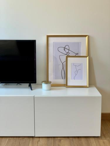 un televisor y dos cuadros en una cómoda blanca en DIJON CENTRE VILLE : SUPER APPARTEMENT NEUF, en Dijon