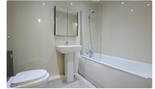La salle de bains est pourvue de toilettes, d'un lavabo et d'une baignoire. dans l'établissement Spacious modern flat in Luton town centre, à Luton