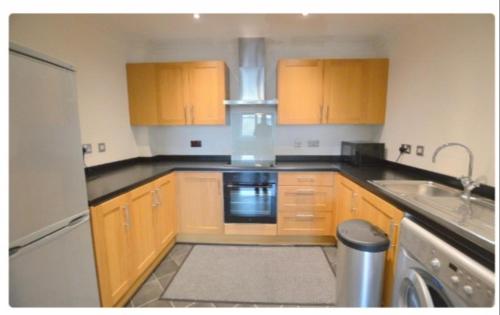 a small kitchen with wooden cabinets and a dishwasher at Spacious modern flat in Luton town centre in Luton
