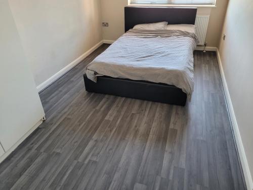 a bedroom with a bed and a wooden floor at Spacious modern flat in Luton town centre in Luton