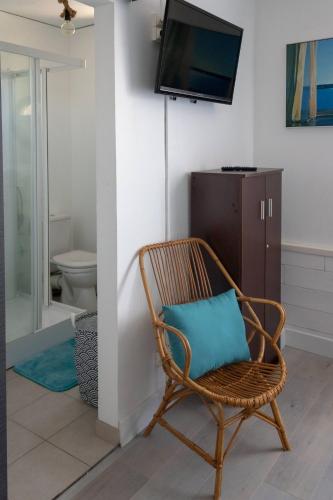 - une chaise en osier avec un oreiller bleu dans la salle de bains dans l'établissement Les chambres aux portes de l'Authie, à Fort-Mahon-Plage