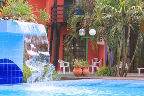 a swimming pool with a fountain in front of a building at Chalés Saint Germain in Florianópolis