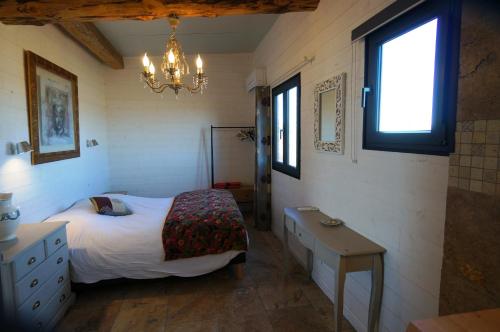 een slaapkamer met een bed, een tafel en een kroonluchter bij Gîtes Equestres Lou Caloun - Les Saintes Maries de la Mer in Saintes-Maries-de-la-Mer
