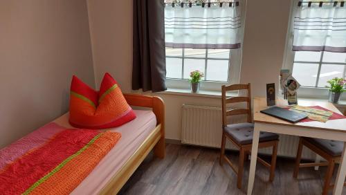 een slaapkamer met een bed met kleurrijke kussens en een bureau bij Pension Bartoschewitz in Lenzen