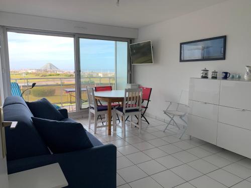 - un salon avec un canapé bleu et une table avec des chaises dans l'établissement Cap sud vue panoramique sur mer et terre, à Le Touquet-Paris-Plage