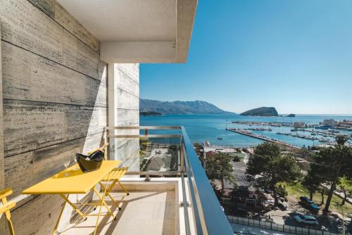 a balcony with a yellow desk and a view of the ocean at Fontana Residence Budva in Budva