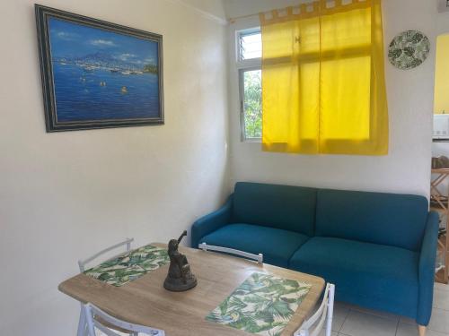 ein Wohnzimmer mit einem Tisch und einem blauen Sofa in der Unterkunft Appartement Orchidée 2 in Fort-de-France