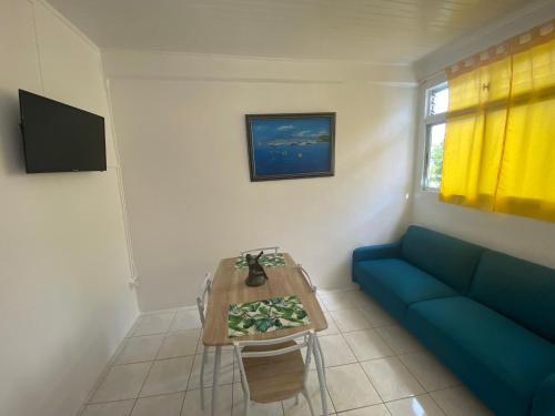 ein Wohnzimmer mit einem blauen Sofa und einem Tisch in der Unterkunft Appartement Orchidée 2 in Fort-de-France