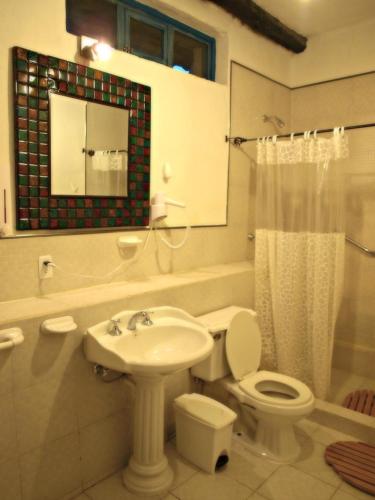 a bathroom with a sink and a toilet and a mirror at Hotel Boutique Casa de Hacienda Su Merced in Puembo
