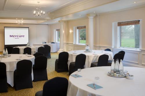 a conference room with tables and chairs and a screen at Winchester Wessex Hotel by Sunday in Winchester