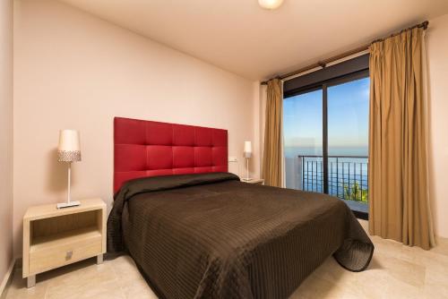 Un dormitorio con una cama roja y una gran ventana. en Apartamento Vista mar frontal, en Torrox Costa