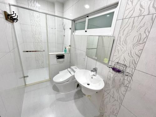 a white bathroom with a toilet and a sink at Yi-Shiou Home in Taitung City