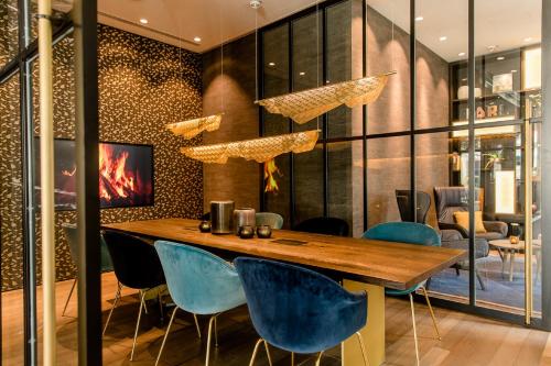 a dining room with a wooden table and blue chairs at Motel One Aachen in Aachen