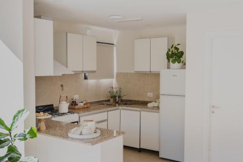 La cuisine est équipée de placards blancs et d'un réfrigérateur blanc. dans l'établissement El Coiron Aparts, à Esquel
