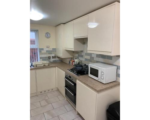 a kitchen with white cabinets and a microwave at Marley Mansions Apartment - Egremont Promenade - 42 in Wallasey