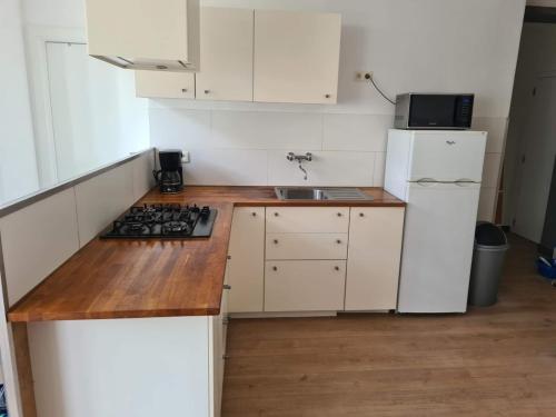eine kleine Küche mit weißen Schränken und einem Waschbecken in der Unterkunft Appartement avec parking 50 m de la mer in De Panne