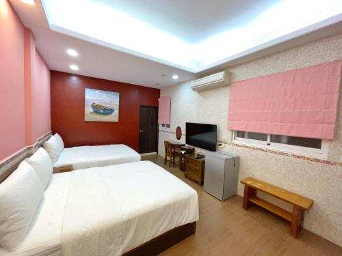 a hotel room with two beds and a flat screen tv at Yi-Shiou Home in Taitung City
