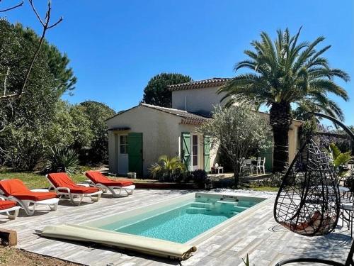 a swimming pool with orange chairs and a house at Gite de l'Amandari - classé 3 etoiles Prefecture - piscine chauffée privative, terrasses et jardin, 5 minutes à pied du village in Plan-de-la-Tour