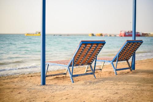 two chairs sitting on the beach near the water at Hotel & Resort Golden Marina Yanbu in Yanbu