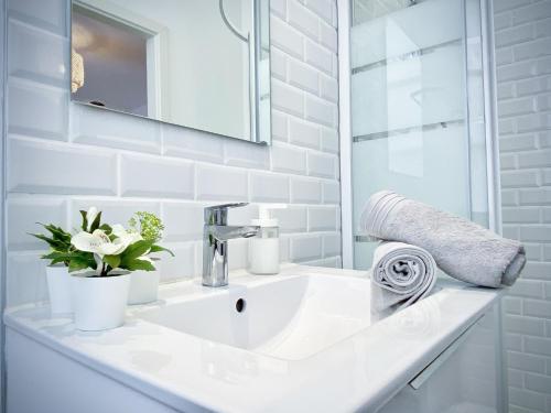 une salle de bain blanche avec un lavabo et un miroir dans l'établissement Le convivial, appartement Centre ville Mulhouse, à Mulhouse