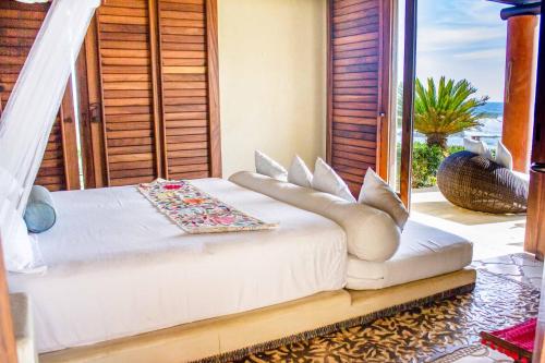 a white bed in a room with a window at Irekua Beach House Ixtapa in La Union de Isidoro Montes de Oca
