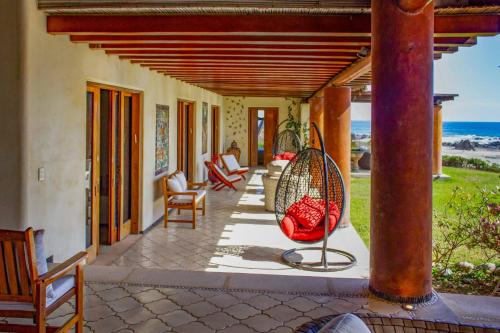 a porch of a house with chairs and a swing at Irekua Beach House Ixtapa in La Union de Isidoro Montes de Oca