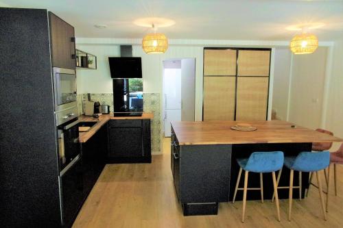 a kitchen with a wooden island with blue bar stools at Duplex House With Large Terrace And Garden in Moliets-et-Maa