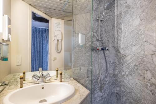 La salle de bains est pourvue d'un lavabo et d'une douche. dans l'établissement Hôtel Baudelaire Opéra, à Paris
