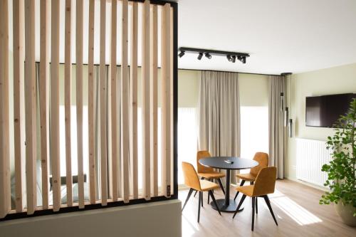 バストーニュにあるAppart hôtel En Villeのテーブル、椅子、テレビが備わる客室です。