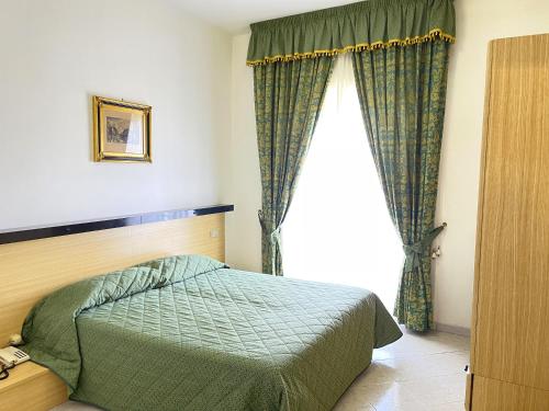 a bedroom with a green bed and a window at Hotel Reginella in SantʼAgata sui Due Golfi