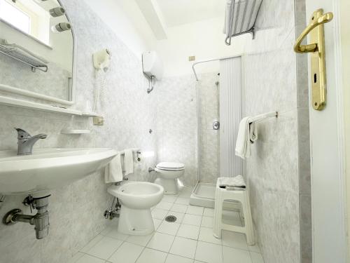 a white bathroom with a sink and a toilet at Hotel Reginella in SantʼAgata sui Due Golfi