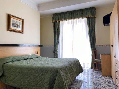 a bedroom with a green bed and a large window at Hotel Reginella in SantʼAgata sui Due Golfi