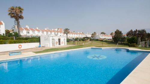 une grande piscine bleue en face d'un bâtiment dans l'établissement Happy Beach House, à Manilva