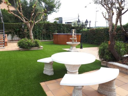 un jardín con 2 mesas blancas y una fuente en Family House - La Mora Beach - Tarragona, en Tarragona