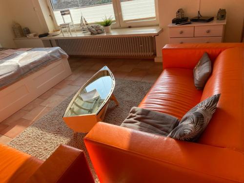 ノルデンにあるFerienwohnung Hillas Töwerhuus in Norddeichのリビングルーム(オレンジ色のソファ、床にボート付)