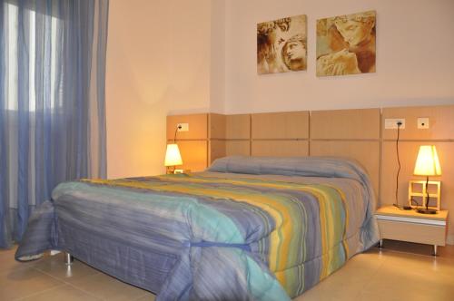 1 dormitorio con 1 cama con 2 lámparas y 2 fotografías en APCOSTAS Marina D'or 1era línea - vista lateral mar, en Oropesa del Mar