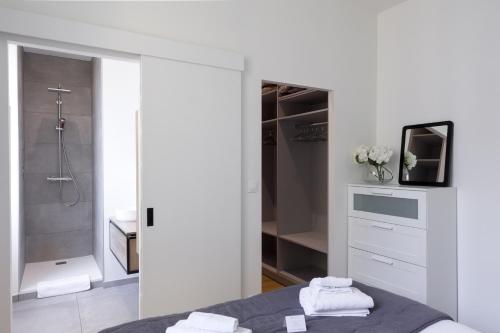 Elle comprend un lit et une salle de bains blanche pourvue d'une douche. dans l'établissement L'AUBELYNE - Chic T2 quartier préfecture, à Lyon