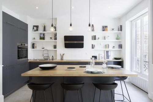 une cuisine avec un grand îlot et des tabourets de bar dans l'établissement L'AUBELYNE - Chic T2 quartier préfecture, à Lyon