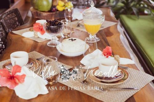 a wooden table topped with plates and cups and drinks at Villa Nicolle - Bahia - Praia do Espelho in Praia do Espelho