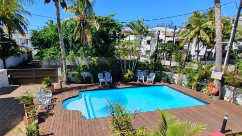 einen Pool in einem Resort mit Palmen in der Unterkunft Les Cerisiers - Exclusive Beach Residence - 3 Bedroom Modern Apartment, Flic en Flac in Flic-en-Flac