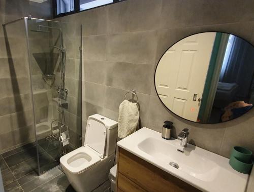ein Badezimmer mit einem WC, einem Waschbecken und einem Spiegel in der Unterkunft Les Cerisiers - Exclusive Beach Residence - 3 Bedroom Modern Apartment, Flic en Flac in Flic-en-Flac