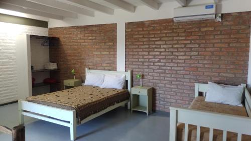 um quarto com uma cama e uma parede de tijolos em Solar Del Valle em Zonda
