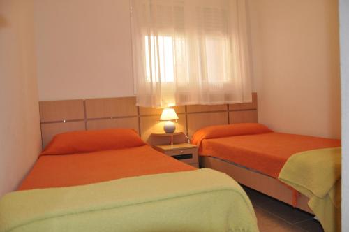 a bedroom with two beds with orange sheets and a window at APCOSTAS Marina D'or 2da Línea in Oropesa del Mar