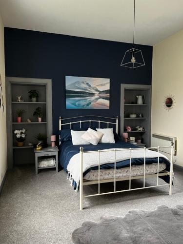 - une chambre avec un lit et un mur bleu dans l'établissement The Sheriffs Lodge, à Dingwall