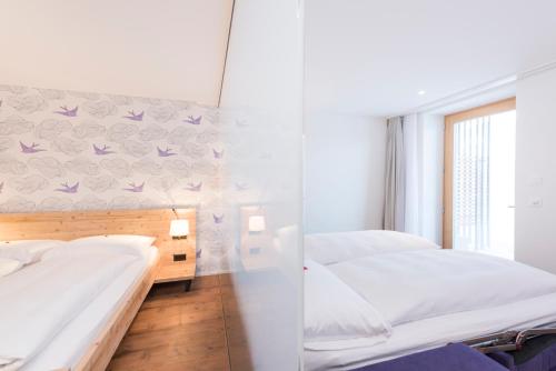 a bedroom with two beds and a wall with purple butterflies at Randolins Familienresort in St. Moritz