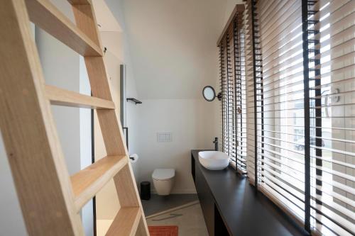 a bathroom with a sink and a toilet and a window at stek&stoof in Sint-Pauwels