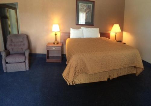 a hotel room with a bed and a chair at Sunflower Inn & Suites - Garden City in Garden City